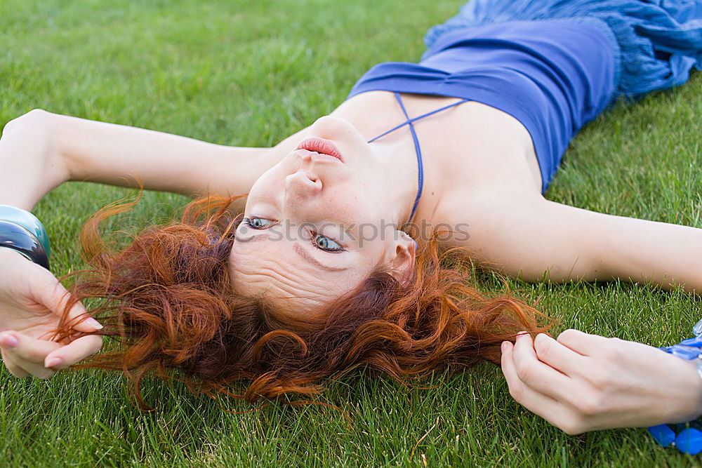 Similar – smiling portrait of a beautiful young sexy redhead woman spreading red hair fan-shaped lying relaxing on the green grass, upside down, copy space