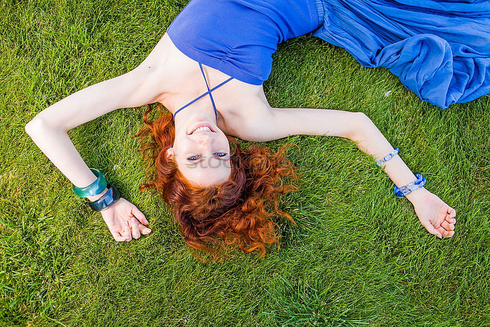 Similar – smiling portrait of a beautiful young sexy redhead woman spreading red hair fan-shaped lying relaxing on the green grass, upside down, copy space