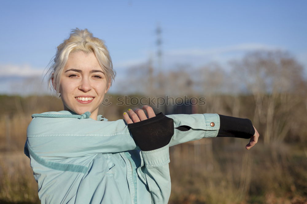 A beautiful young blonde woman stretching in a park