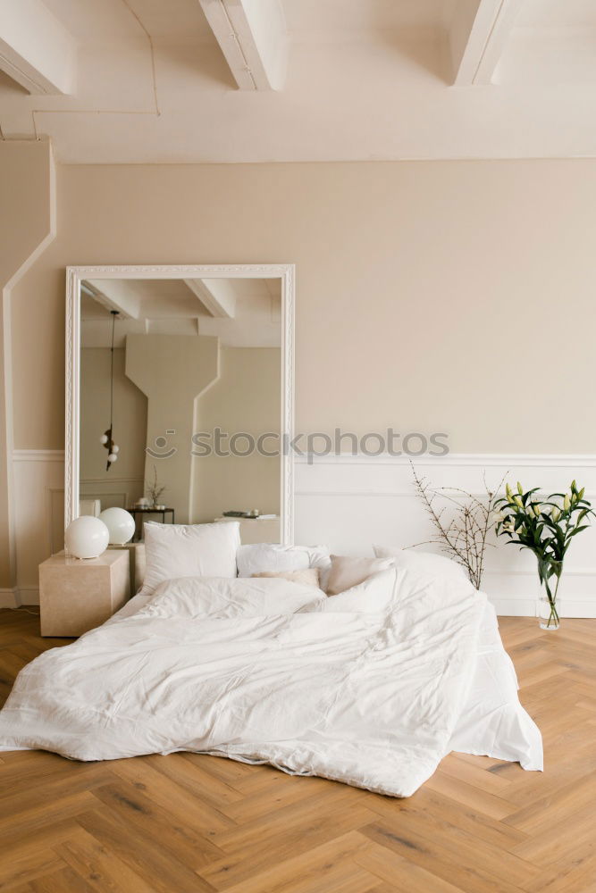 Similar – Ein Doppelbett mit weißer Bettwäsche und beigen Kissen in einem hellen skandinavischen Schlafzimmer, ein Bett auf dem Boden und Blumen in einer Vase