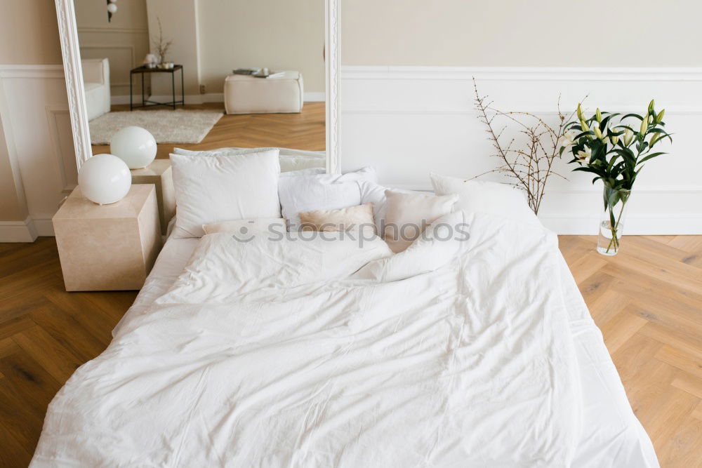 Similar – Ein Doppelbett mit weißer Bettwäsche und beigen Kissen in einem hellen skandinavischen Schlafzimmer, ein Bett auf dem Boden und Blumen in einer Vase