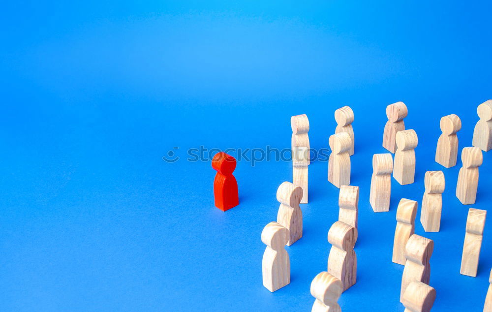 Similar – A red playing figure stands together with white playing figures in a circle on a blue background