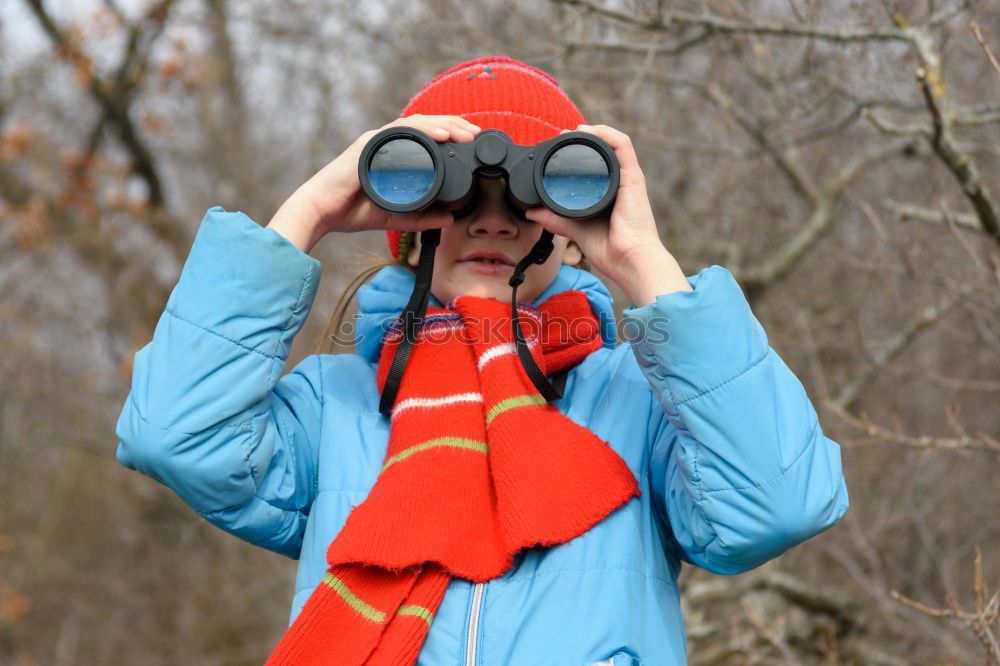 rothaariger hübscher Teenager, langhaarig mit schwarzer Sonnenbrille, blauer Jacke, orangefarbenem Schirm im Wald