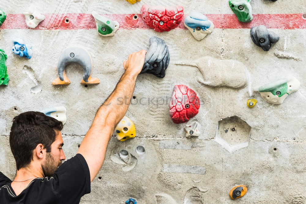 Similar – Man practicing rock climbing on artificial wall indoors.