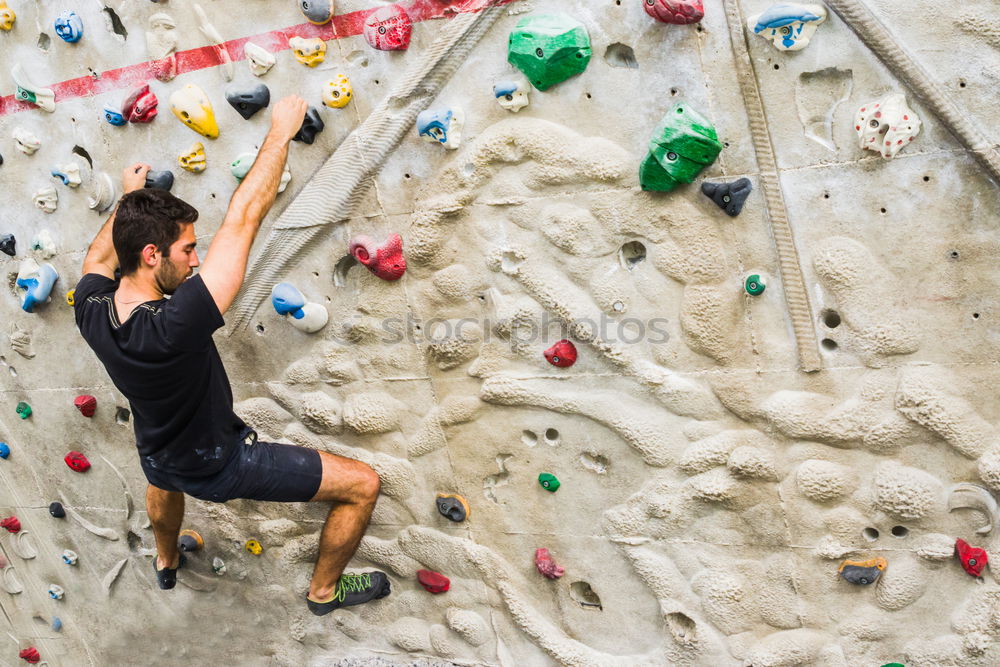 Similar – Man practicing rock climbing on artificial wall indoors.