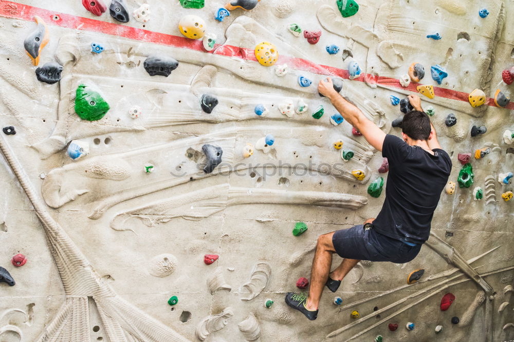 A Man practicing rock climbing on artificial wall indoors