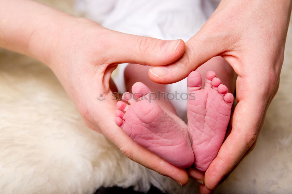 Similar – mother and father holding newborns feet in a heart shape