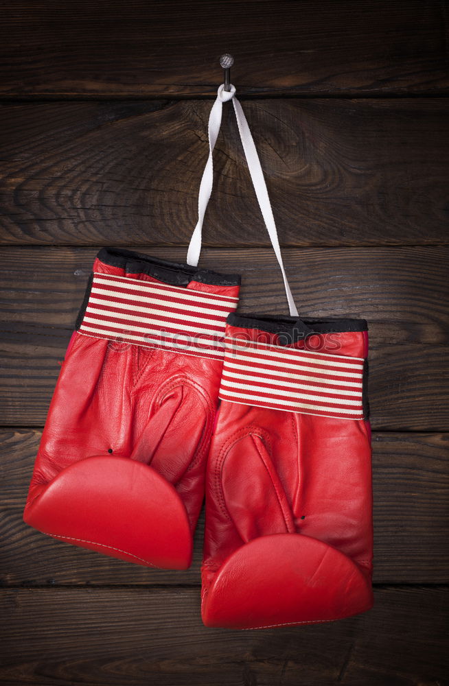 red leather boxing gloves hang on a nail