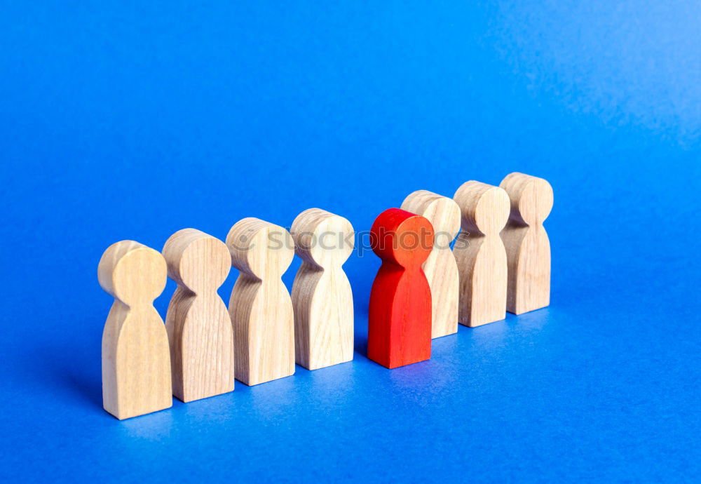 Similar – A red playing figure stands together with white playing figures in a circle on a blue background