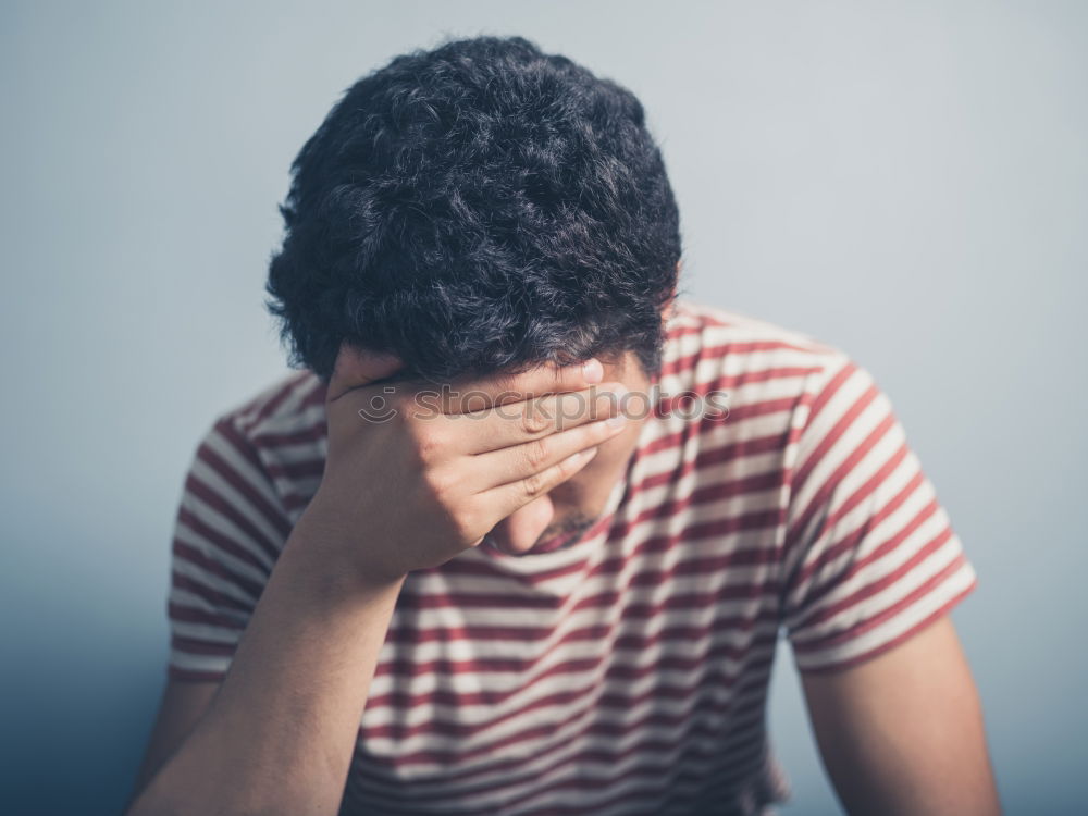 Similar – one sad woman sitting near a wall and holding her head in her hands