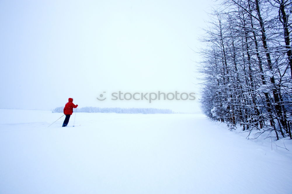 Similar – Winter weather, a ski hiker follows a marked trail through a snowy mountain landscape