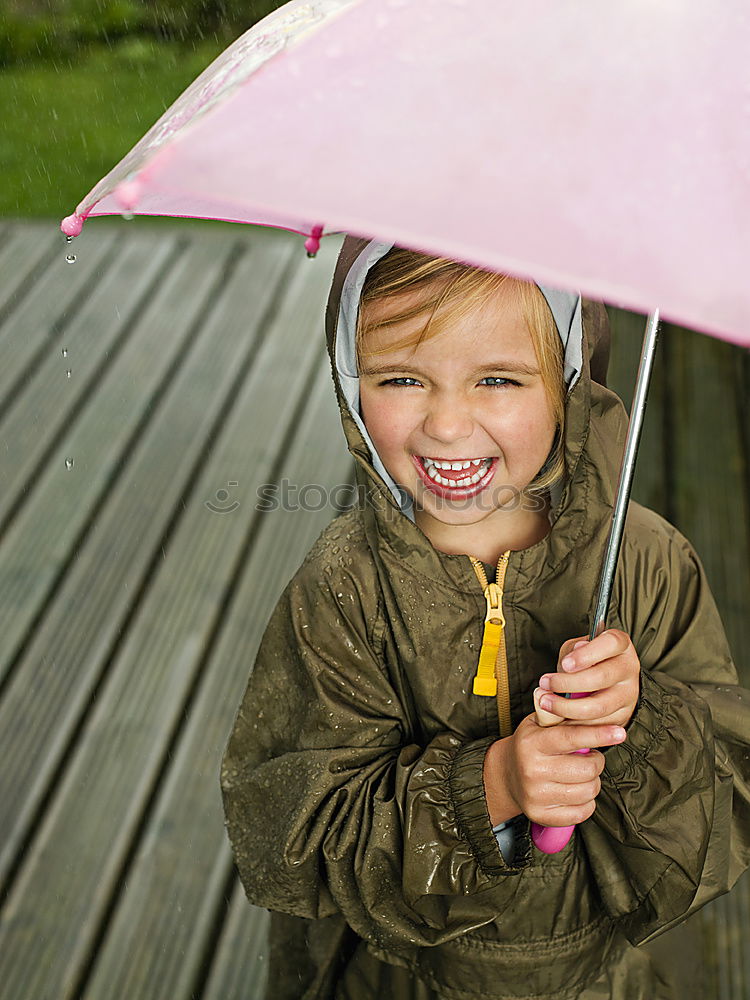 Similar – Image, Stock Photo Child in a raincoat with umbrella crouched down playing and laughing in a puddle