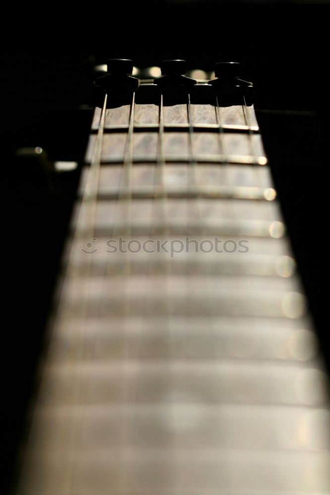 Image, Stock Photo A black electric guitar on a wooden board table photographed from the guitar head perspective. The focus is on the side holder and knob.