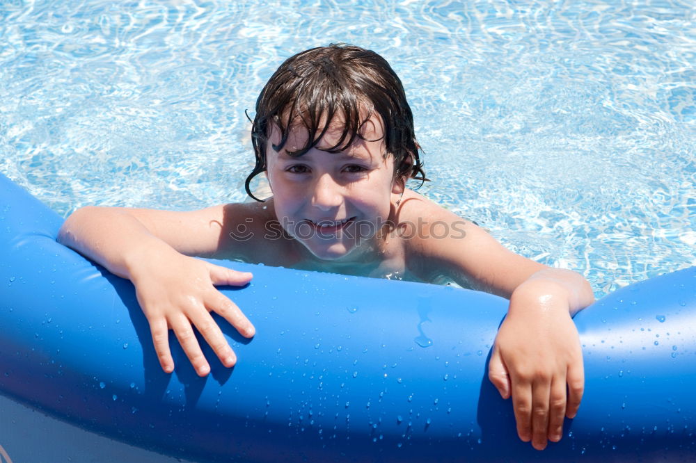 Happy little girl floating with a ring in the water