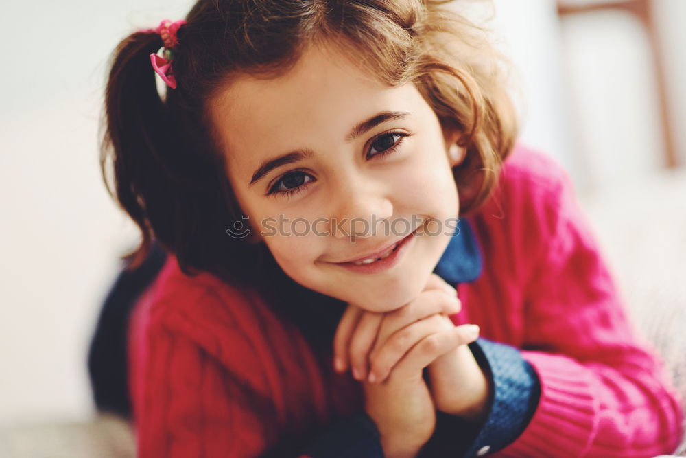 Adorable little girl with sweet smile lying down on bed.