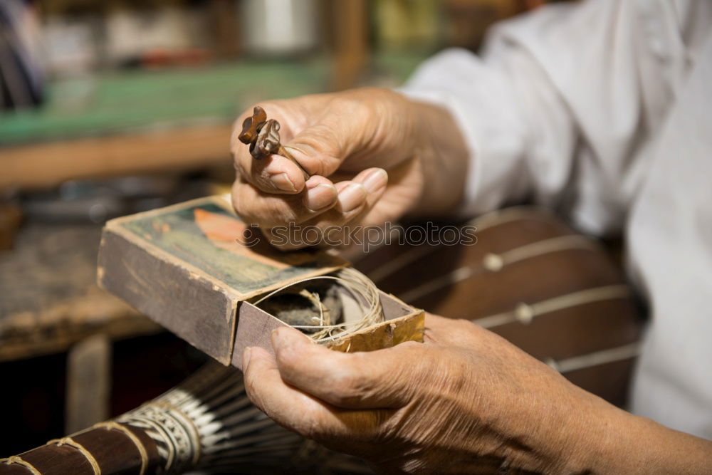 man’s hands goldsmith work on a piece of silver