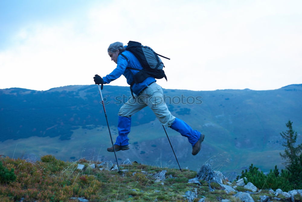 Similar – Woman walking in the mountains with sticks in her hands