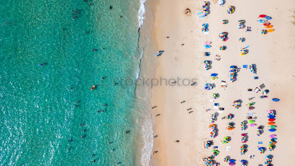 Drone shot of many people enjoying the beach and the ocean in high season- vacation pattern.