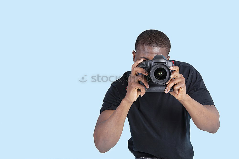 Young modern man sitting on halfpipe taking picture with Camera