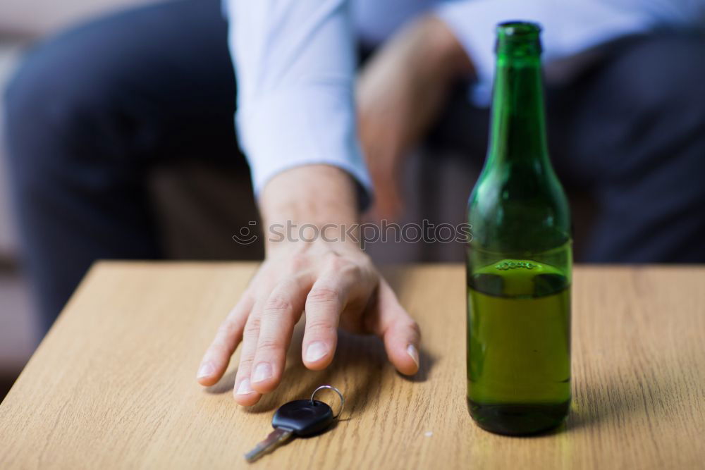 Similar – On a table there is a bottle of alcohol and a shot glass. A person’s hand is holding the shot glass.