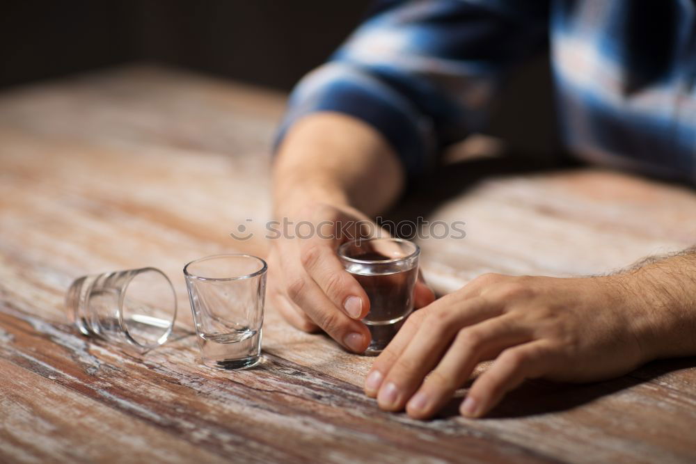 Similar – On a table there is a bottle of alcohol and a shot glass. A person’s hand is holding the shot glass.