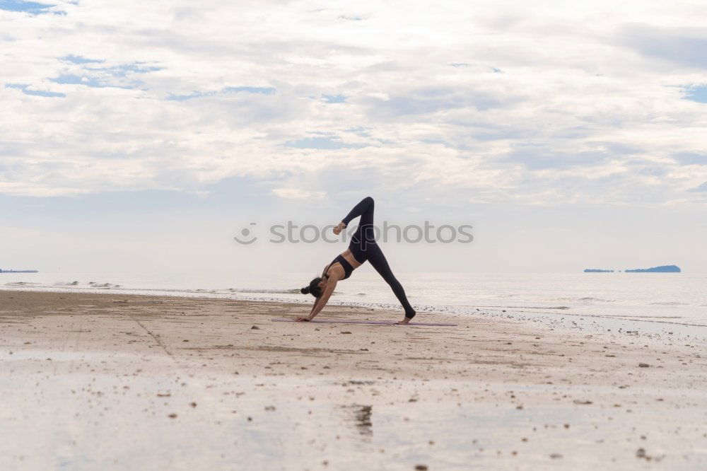 Similar – Young woman building bridge on beach backlit in front of massive cliff