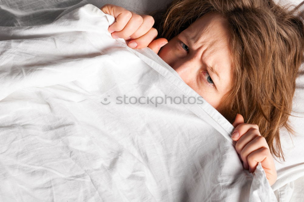 Portrait of an attractive, young, sexy dark haired woman in Bed, hand and head on the pillow under the blanket, Copy space.