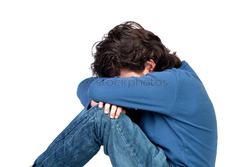 one sad woman sitting near a wall and holding her head in her hands