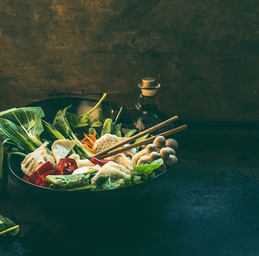 Asian food. Wok pan with colorful ingredients for korean vegetarian one pot. Dumpling hot pot preparation on dark kitchen table . Healthy vegan eating and cooking