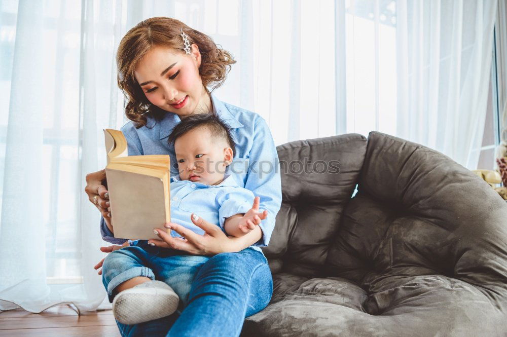 Similar – Mom reading a book her little daughter