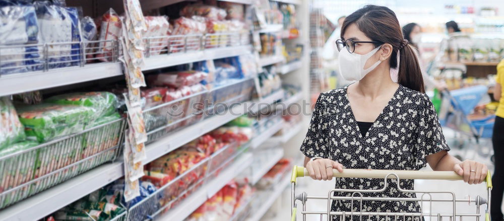 Similar – Image, Stock Photo A smiling middle aged woman in a light blue shirt is standing in a household section of a supermarket. She is holding a tablet and a red shopping basket in her hands. A woman is looking at the shelves, searching for something particular