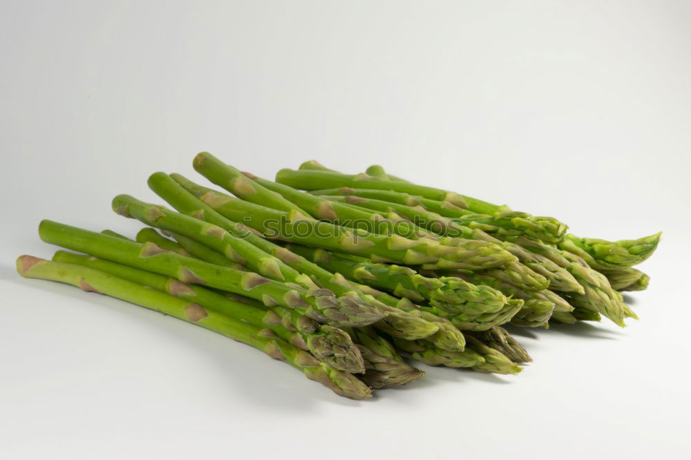 Similar – Image, Stock Photo A portion of green asparagus, freshly harvested from the local field, decorated with a plaid ribbon of cloth, tied together, lies in the light on the table, on a white cloth of linen.