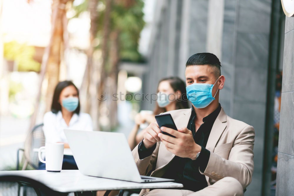 Young Businessman Wearing Mask Working On Laptop At Hot Desk In Office During Health Pandemic