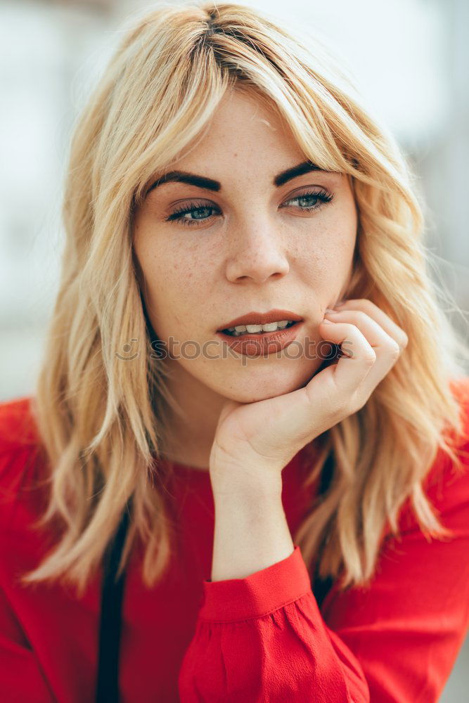 Smiling blonde girl with red shirt enjoying life outdoors.