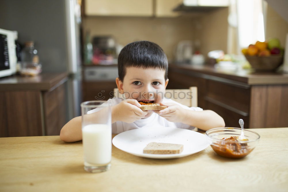 Similar – Little boy in a cafe during lunch. Hungry kid eating sausage from his sandwich