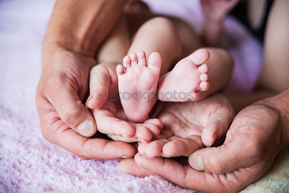 Baby girl touching hand of senior man