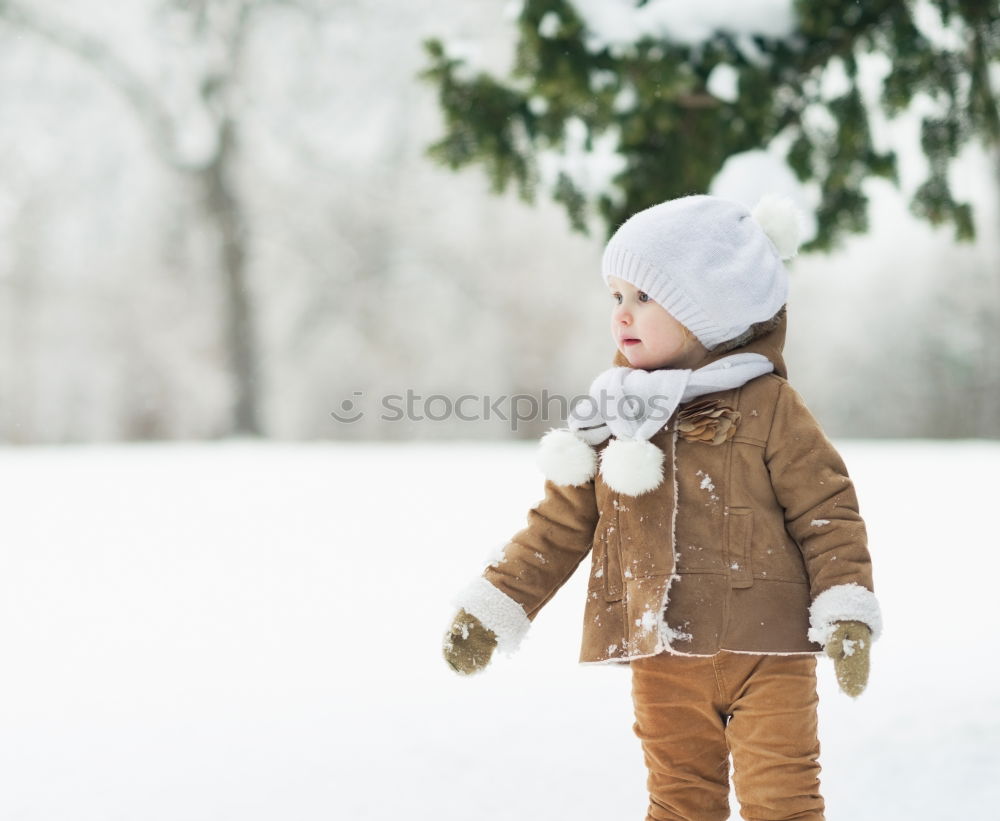 Similar – baby girl in knitted scarf walking in winter forest