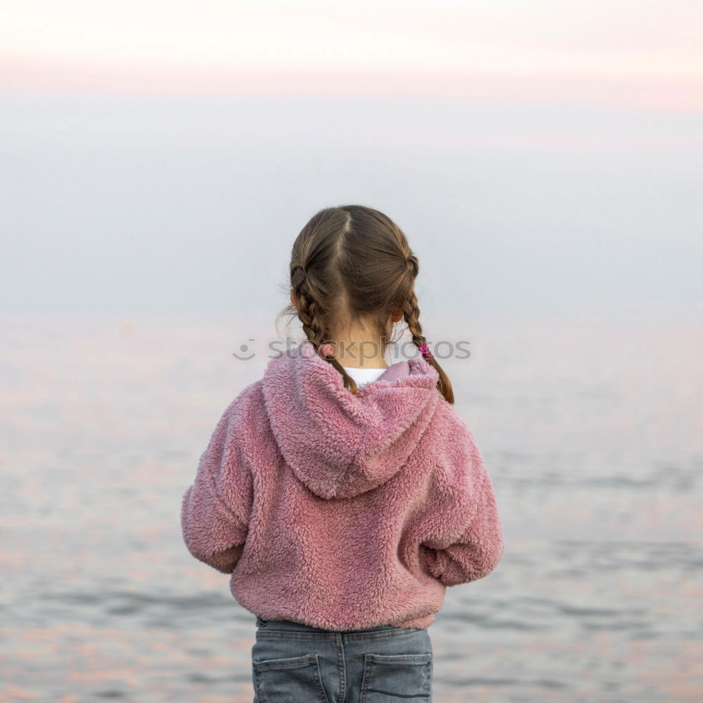 Similar – Child sitting by the sea with a view of a jetty