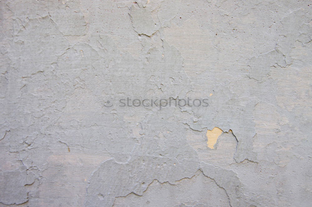 A piece of white adhesive tape over a crack in the plaster of a house wall