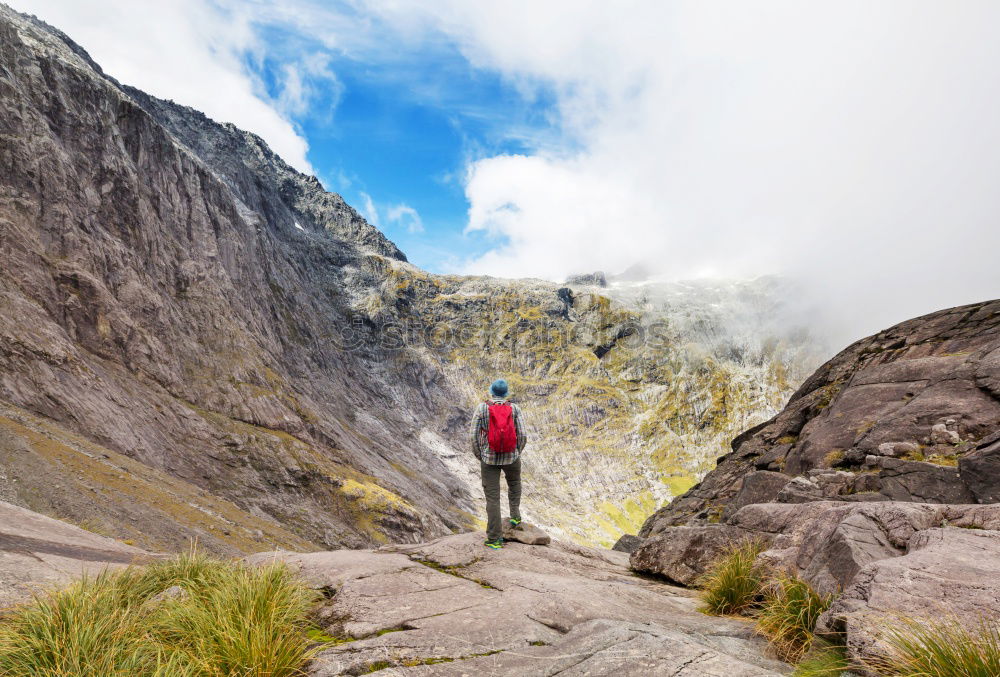 Similar – Young woman with hiking backpack stands on the edge of rain covered valley