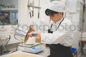 Similar – Image, Stock Photo A cook in a restaurant wearing a mask as a precaution against the coronavirus preparing the meal.