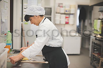 Similar – Image, Stock Photo A cook in a restaurant wearing a mask as a precaution against the coronavirus preparing the meal.