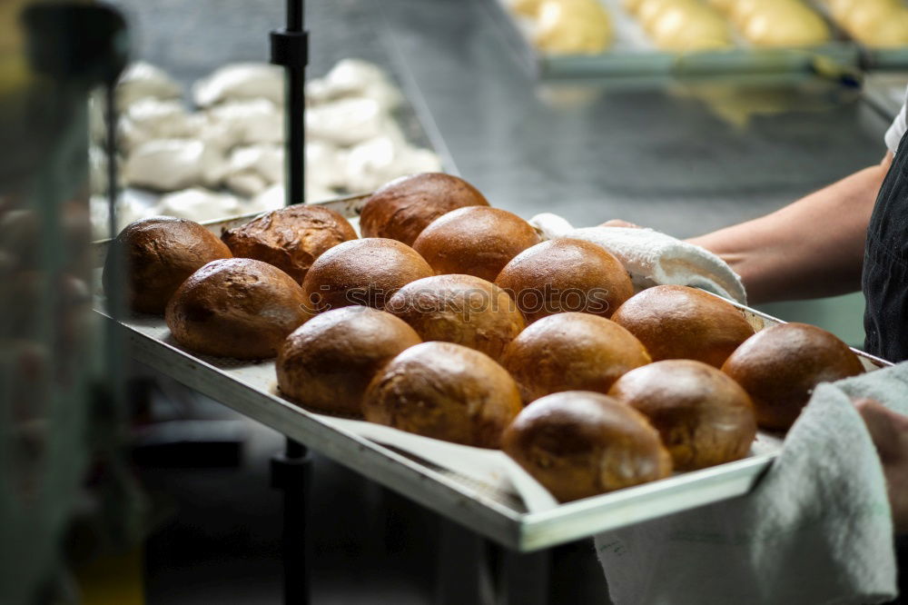 Similar – Fresh loaves of bread on tray racks. Bread bun on bakery shelves