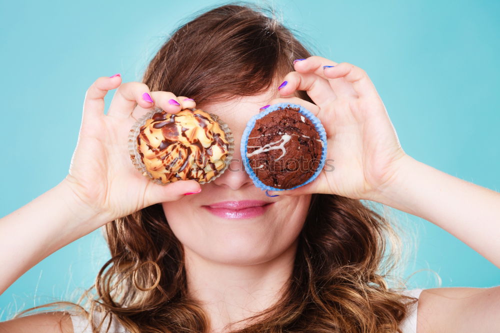 Young woman pulling funny face holding donuts in hands