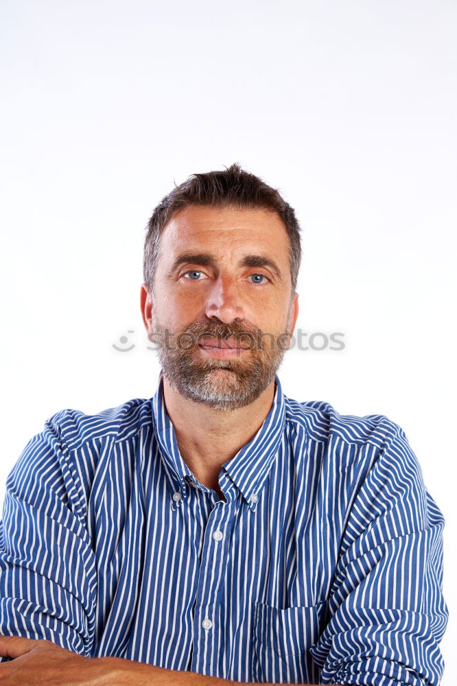 Portrait of a smiling senior with grey hair and grey beard in front of a grey sky