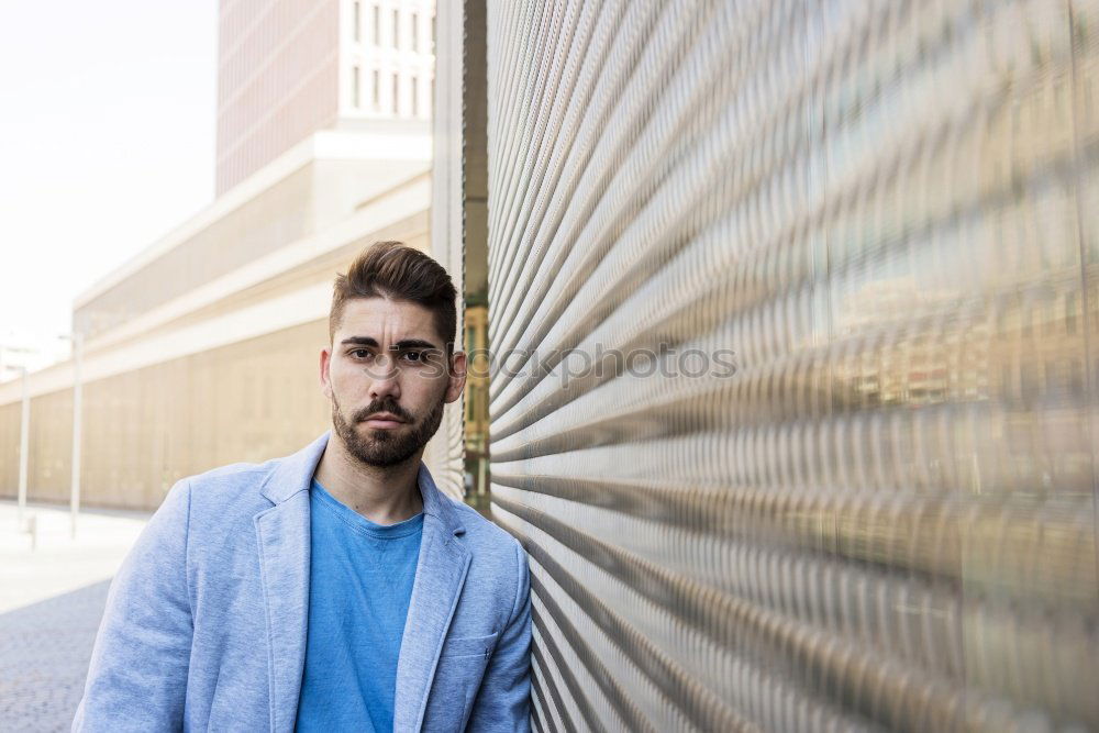 Similar – Young bearded man in urban background wearing casual clothes while leaning on a wall and looking at camera