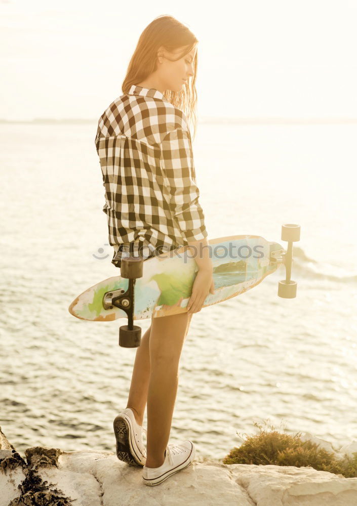 Man standing with skateboard at shore