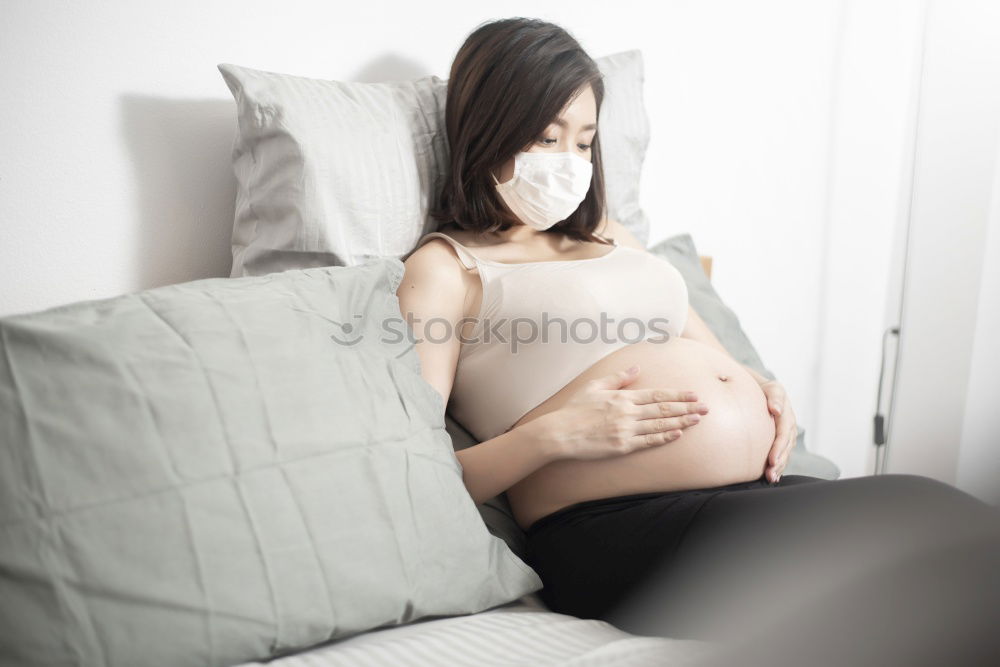 Similar – Happy pregnant woman sitting and touching her belly at home