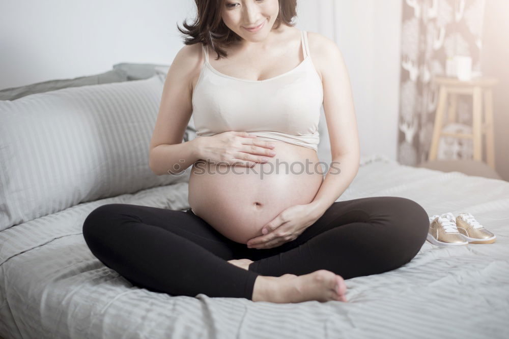 Similar – Happy pregnant woman sitting and touching her belly at home