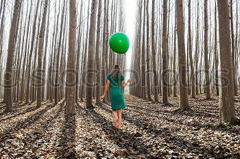 Beautiful blonde girl, dressed in green, standing in the forest